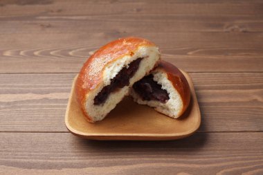 anpan round bread with azuki red beans paste isolated on plate on wooden table