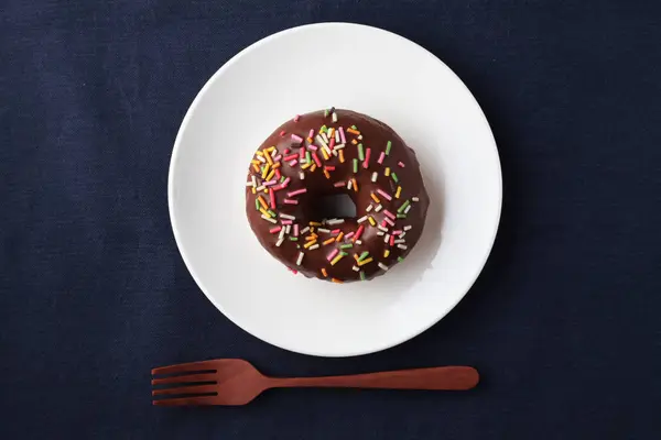 Chocolate frosted doughnut on plate on table — Stock Photo, Image