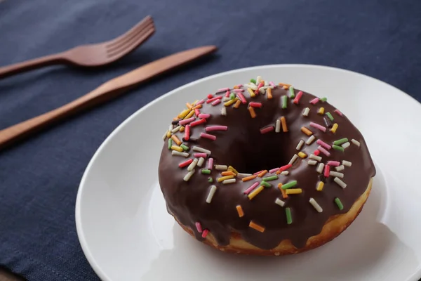 Chocolate frosted doughnut on plate on table — Stock Photo, Image