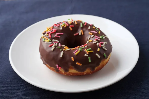 Chocolate frosted doughnut on plate on table — Stock Photo, Image