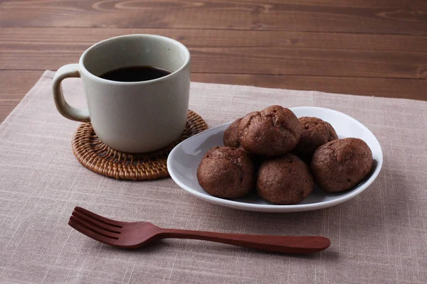 Soplos de crema de chocolate en el plato con café caliente aislado en la mesa de madera — Foto de Stock