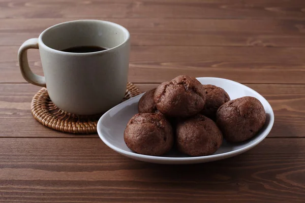 Шоколадні вершкові пуфи на тарілці з гарячою кавою ізольовані на дерев'яному столі — стокове фото