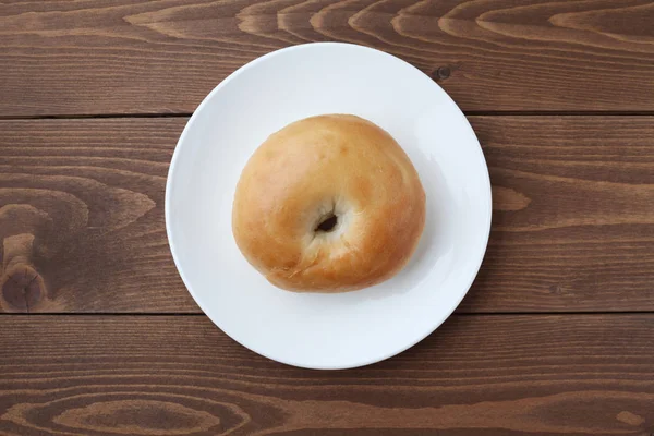 Plain bagel bread on plate isolated on wooden table — 图库照片