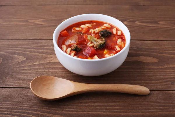 Minestrone vegetables tomato soup with pasta isolated on wooden table — Stock Photo, Image