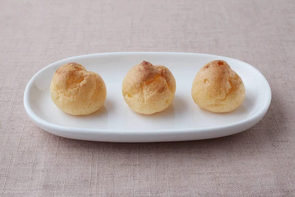 Cream puffs on plate isolated on table cloth — Φωτογραφία Αρχείου