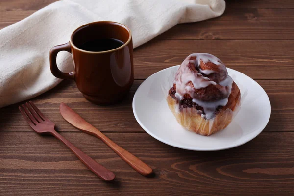 Cinnamon roll bread on plate and hot coffee isolated on wooden table — Stock Photo, Image