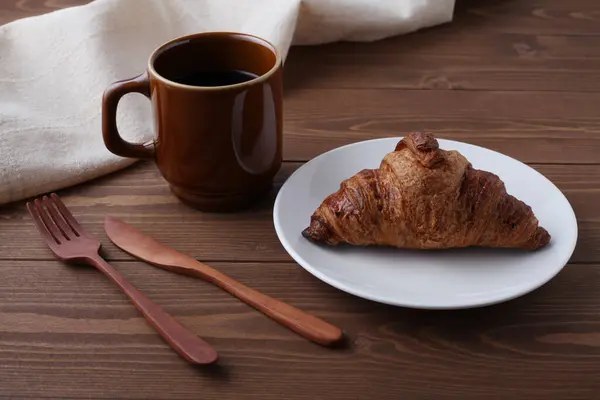 Croissant french bread on plate and hot coffee isolated on wooden table — Stock Photo, Image