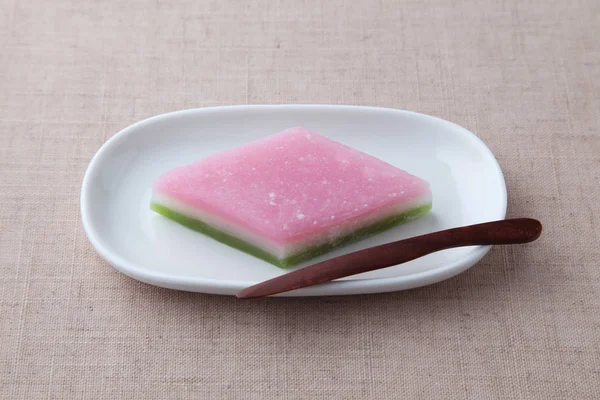 Bolo de arroz tricolor em forma de diamante hishimochi Confeitaria tradicional japonesa na placa isolada na toalha de mesa — Fotografia de Stock