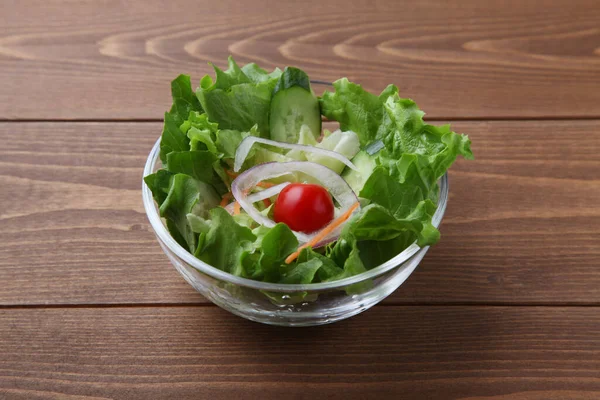 Fresh green lettuce salad in bowl isolated on wooden table — Stock Photo, Image