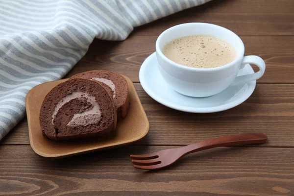 Bolos de rolo de chocolate na placa com xícara de café latte na mesa — Fotografia de Stock