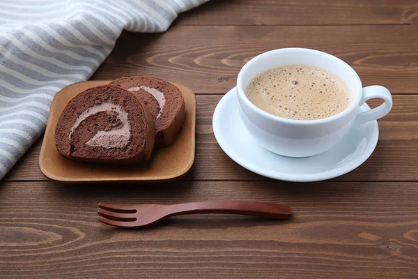 Chocolate roll cakes on plate with cup of cafe latte on table — Stock Photo, Image