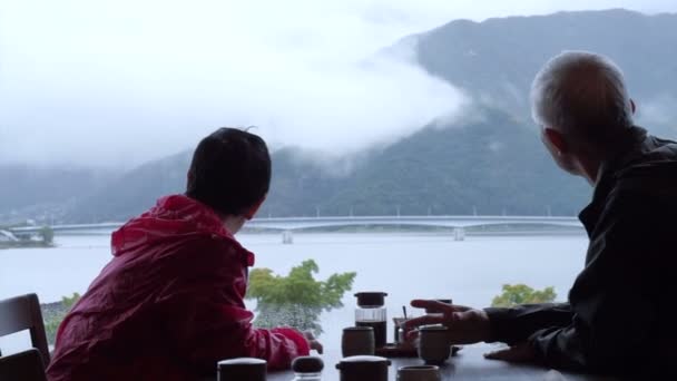 Asiatique couple âgé boire du thé avec belle journée de pluie vue sur la montagne et le lac — Video