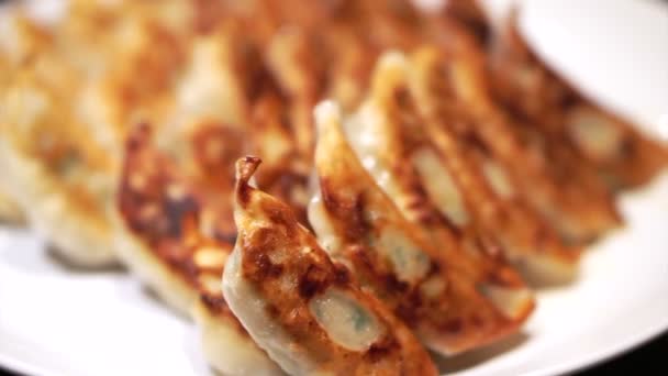 Placa llena de deliciosa gyoza japonesa con una corteza quemada lateral. Comer con palillos — Vídeo de stock