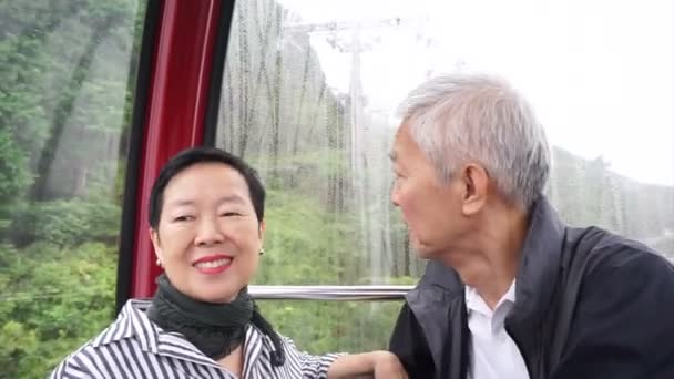 Asiatiska senior par reser på ropewayen linbana upp i bergen för pensionering resa — Stockvideo