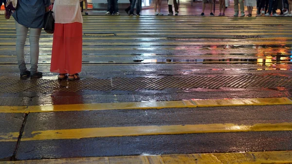 Asiatiques traversent rue humide avec néon réflexion de la lumière — Photo