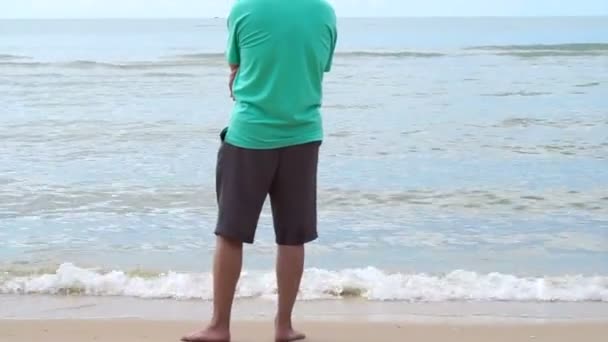 Asian senior man standing alone at the beach thinking about life — Stock video