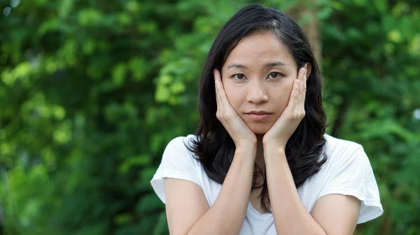 South East Asian girl looking at camera green background — Stock fotografie