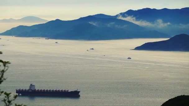 Aerial shot of container cargo ship at beautiful sunset ocean from far — Stockvideo