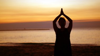Asya kıdemli siluet meditasyon namaste sunrise Beach yapıyor