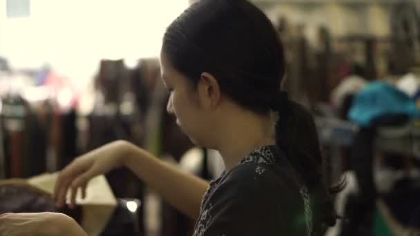 Asijské Smíšené rasy žena nakupování druhá oblečení na bleší trh skladu — Stock video