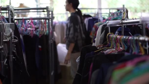 Asian mixed race woman shopping second clothes at flea market warehouse — Stock Video