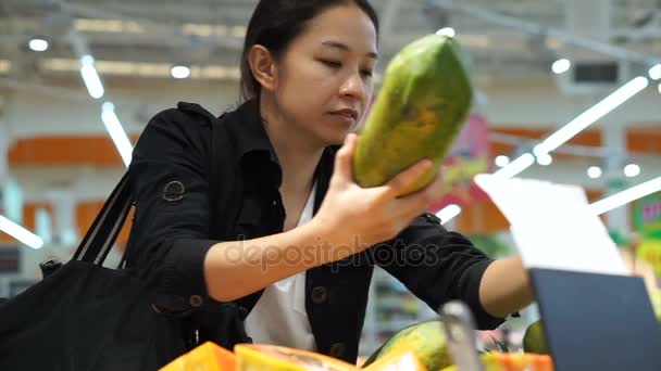Ázsiai bevándorló nő bevásárlás a gyümölcs a szupermarketben. Absztrakt nehéz gazdasági időszakban — Stock videók