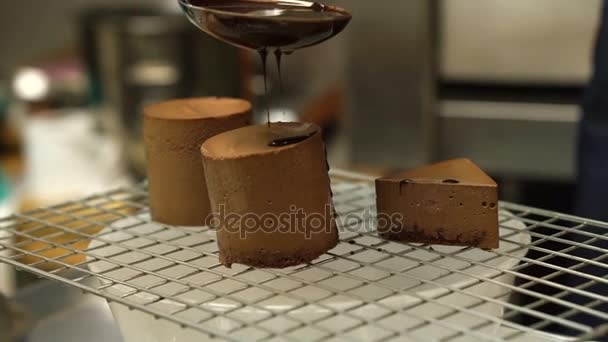 Despejando chocolate derretido no bolo de esponja de assar fresco para esmaltar a tampa — Vídeo de Stock