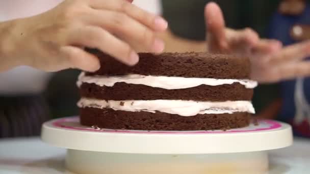 Patisserie chef baking decorating chocolate sponge cake. Putting white cream in the middle layers — Stock Video