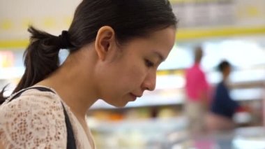 Asyalı kız öğeleri hipermarket, süpermarket raflarında seçer.