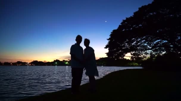 Зрелая азиатская старшая пара празднует годовщину на берегу озера, утреннюю луну и восход солнца — стоковое видео