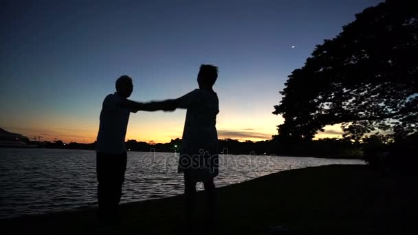 Зрелая азиатская старшая пара празднует годовщину на берегу озера, утреннюю луну и восход солнца — стоковое видео