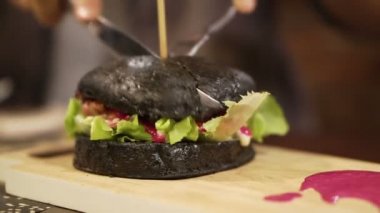 Siyah kömür burger kesilmiş kırmızı sos ile. Yeni trend sağlıklı siyah gıda