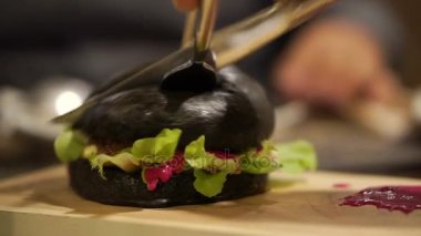 Siyah kömür burger kesilmiş kırmızı sos ile. Yeni trend sağlıklı siyah gıda