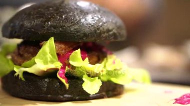 Siyah kömür burger kesilmiş kırmızı sos ile. Yeni trend sağlıklı siyah gıda