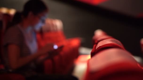 Femme asiatique utilisant un téléphone portable dans un cinéma vide. Éteignez votre téléphone avant le concept du film — Video