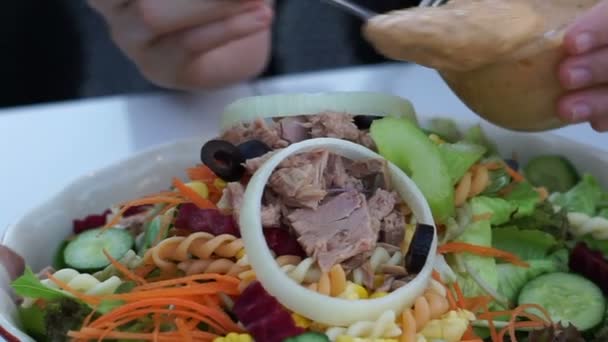 Hand gieten Thousand Island dressing op de top van tonijn salade — Stockvideo