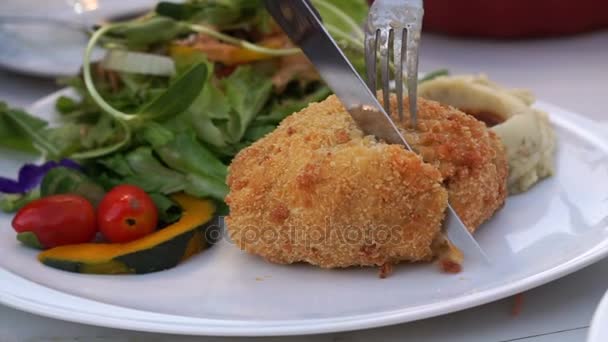 Cuchillo rebanando pollo Cordon bleu con ensalada. Jamón, tocino y queso rellenos dentro de pollo rebozado — Vídeos de Stock
