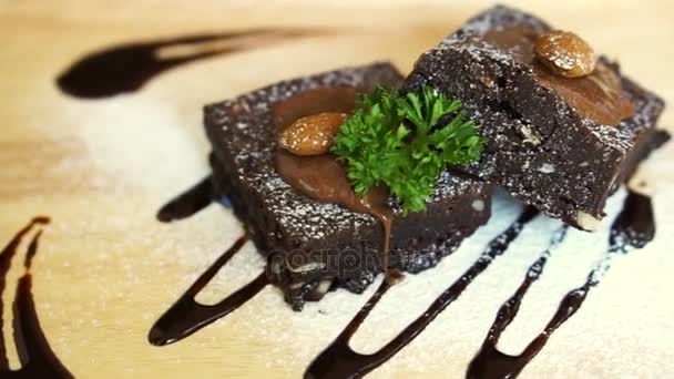 Dark chocolate topping brownie cake. Homemade coffee shop dessert serve on light wood plate — Stock Video