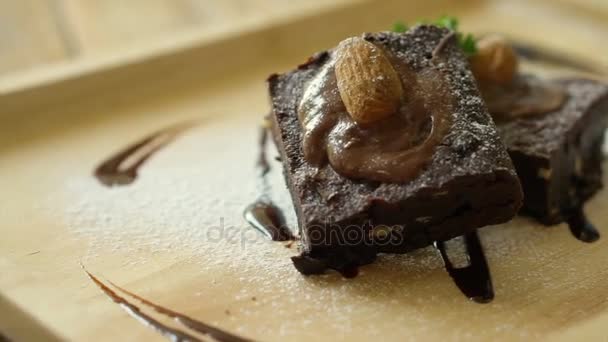 Donkere chocolade topping brownie cake. Zelfgemaakte coffeeshop dessert serveren op lichte houten plaat — Stockvideo