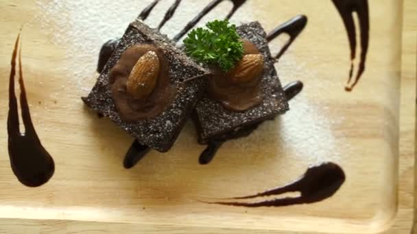 Donkere chocolade topping brownie cake. Zelfgemaakte coffeeshop dessert serveren op lichte houten plaat — Stockvideo