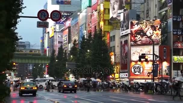 Tokyo, Japan - September 2016: Raining scene in Akihabara, game, manga and electronic world center. People walking with umbrella at the junction with advertising and neon signs — Stock Video