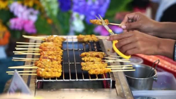 Schweinefleisch Satay thailändischen Lebensmitteln auf dem lokalen Markt. Hand mit Schere ausgebranntes Teil herausgeschnitten — Stockvideo