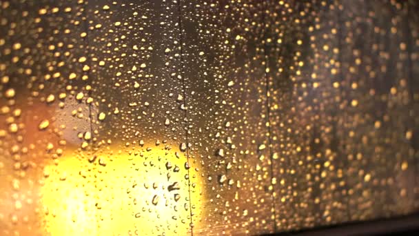 Bokeh luz de oro y gotas de lluvia en el cristal de la ventana — Vídeos de Stock