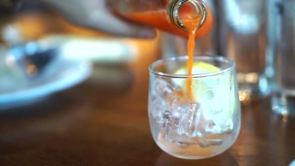 Ömlött mocktail narancslé, citromlé jég pohár étteremben — Stock videók