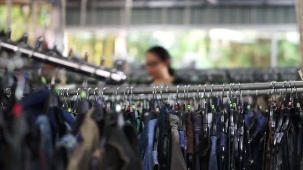 服はドレスと秒針の倉庫店での販売のために掛かっているシャツの多くを持つ行をラックします。 — ストック動画