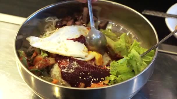 Змішування bibimbap корейські рису і Асорті овочеві страви використовуючи нержавіючої ложкою — стокове відео