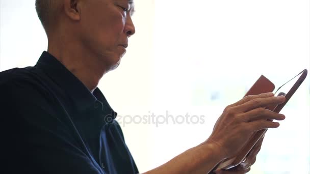 Aziatische senior man voorraad investeringen informatie op tablettechnologie weergeven — Stockvideo