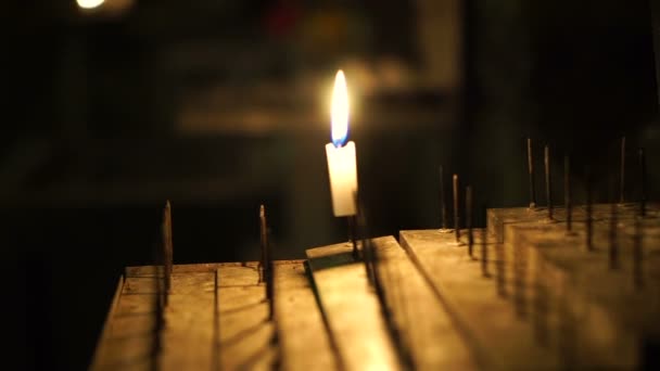 Één kaars verlicht in het donker. Bewegende vlam op heilige stand. Abstracte hoop en wens — Stockvideo