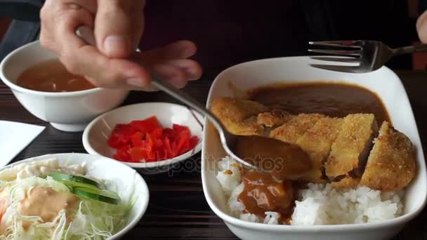 Азиатский парень ест японское карри с тонкацу, жареную свинину в столовой — стоковое видео