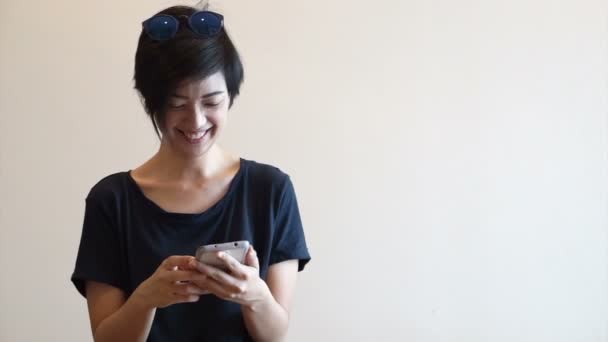 Hűvös ázsiai csípő lány modern megjelenés mosoly és a nevetés, rövid idő használ szúró telefon — Stock videók